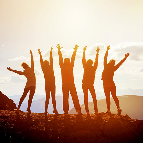 hikers on mountaintop reach for sky